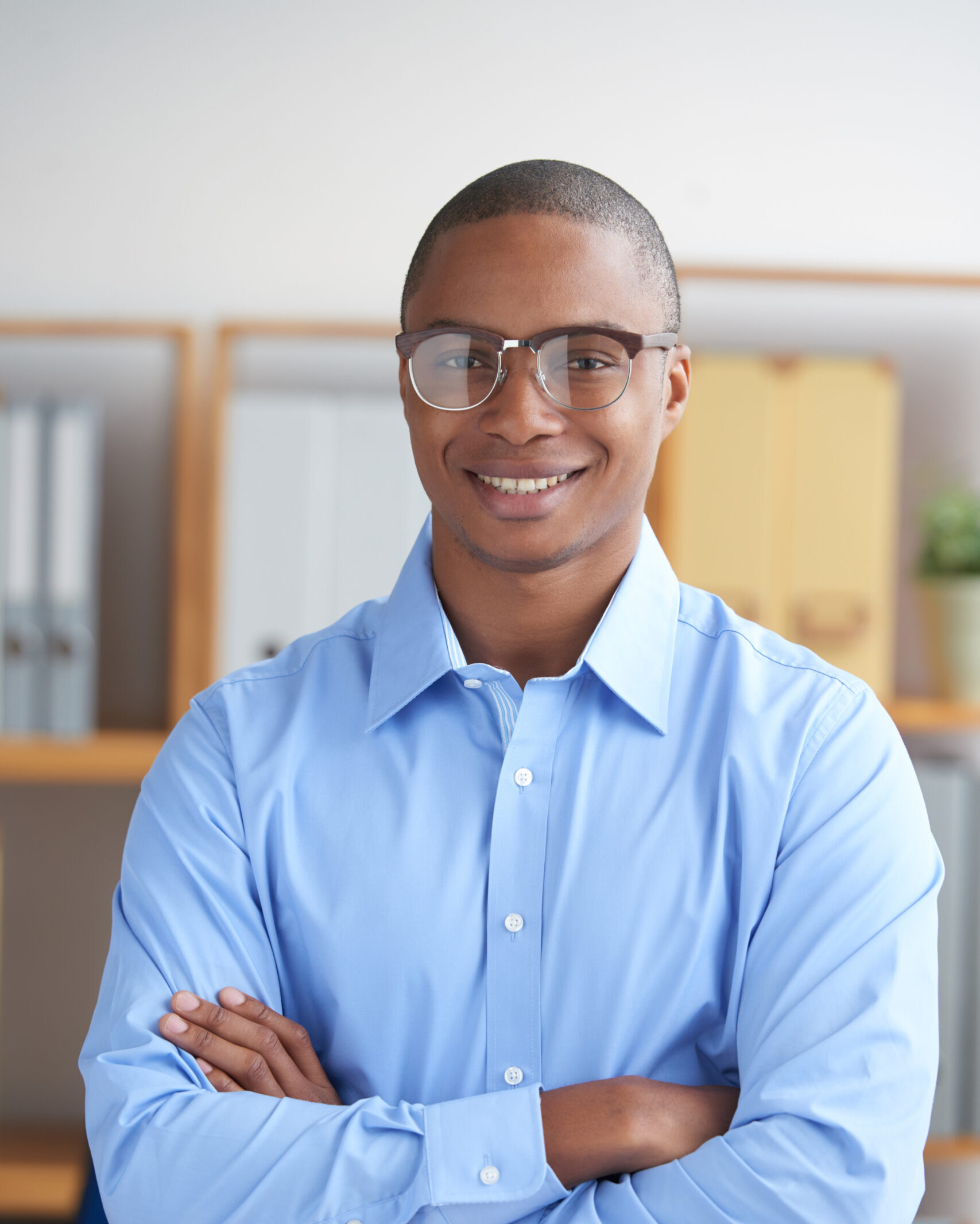 Portrait of confident smiling businessman standing with his arms crossed
